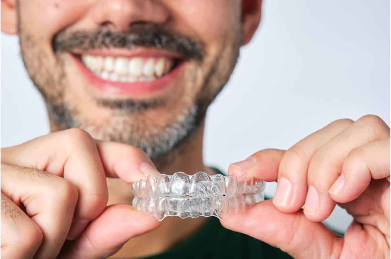 Man holding Invisalign aligners showcasing virtually invisible clear aligners.